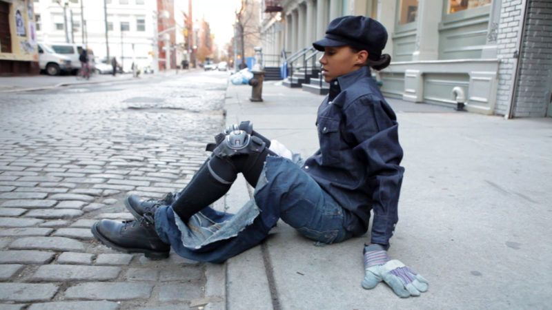 LaToya Ruby Frazier sitting on a curb in New York City rubbing a pair of Levi's against the concrete.
