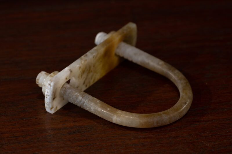 A sculpture made of Nephrite lies on a dark wooden surface.