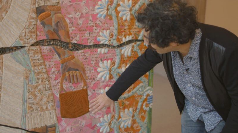 Michael Rakowitz gestures toward a colorful mosaic.