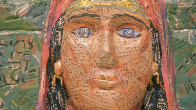 Close-up of a papier-mâché of a woman's face created out of packaging of Middle Eastern food goods.