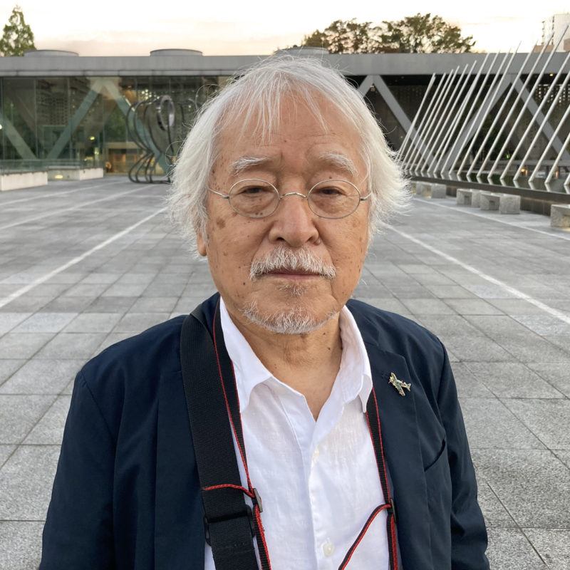 Hiromi Tsuchida looking out at the camera wearing glasses and a blue jacket over a white button-down shirt.